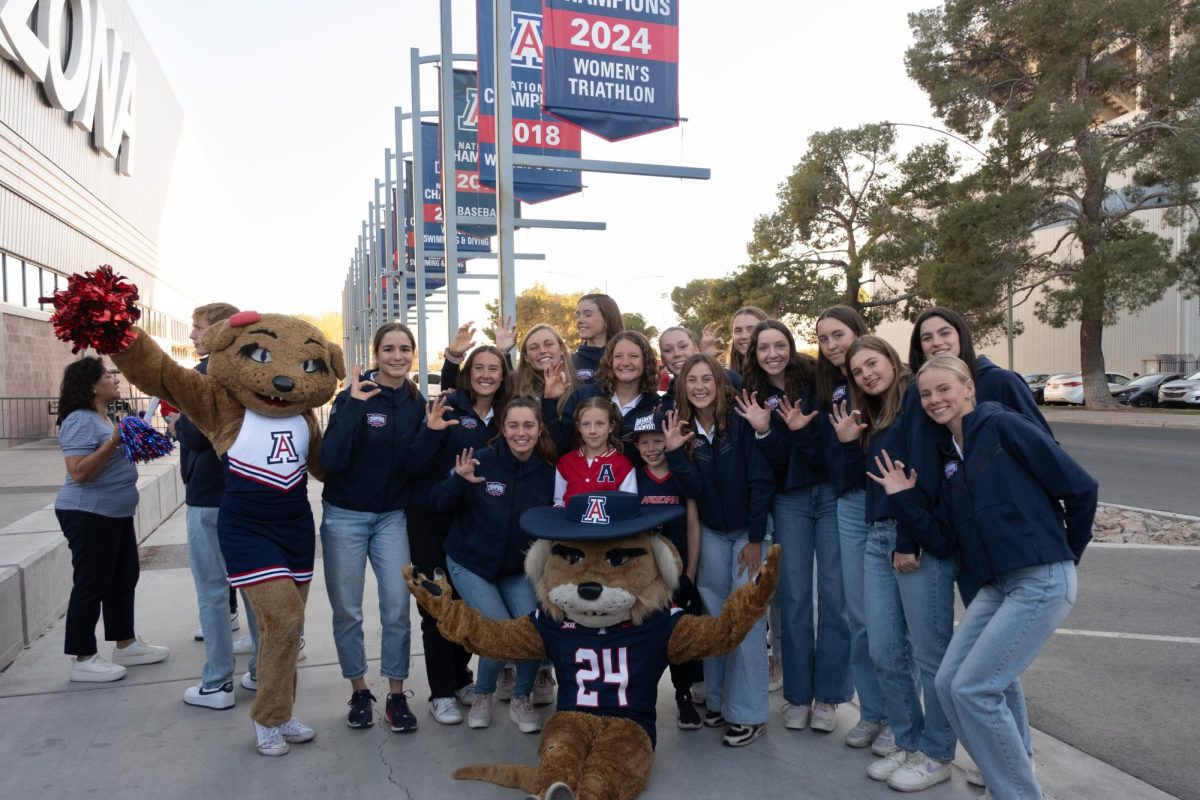 The University of Arizona women's triathlon team poses with Wilma and Wilbur under their national championship banner on Jan. 23 at National Championship Drive. The team is celebrating its first national championship in its second year of existence.