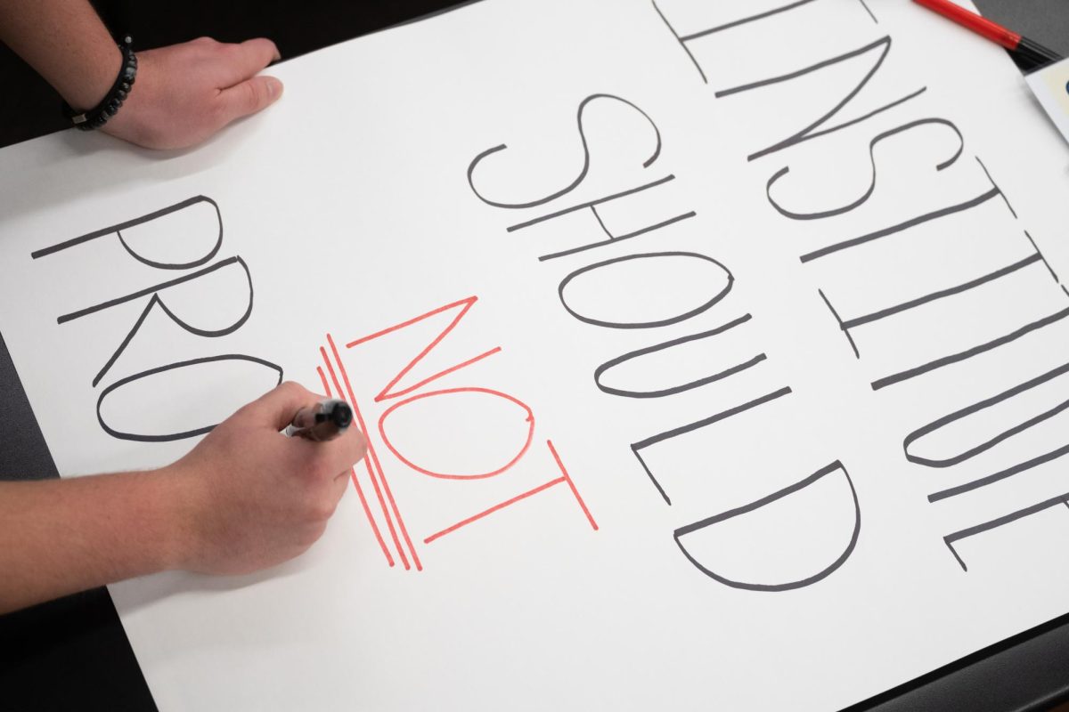 A member of the College Democrats works on his sign during a meeting on Feb. 6. Protesters prepared their signs for protests that were to be held the following week.