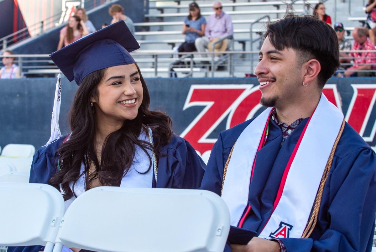 Emma Diaz, a University of Arizona graduate, sits with a friend at Arizona Stadium on May 16, during the university’s commencement ceremony. The two waited as graduates continued filing in behind them.