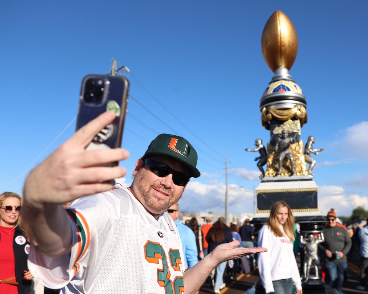 A Miami fan poses with a upscaled replica of the Fiesta Bowl trophy prior to kickoff in State Farm Stadium in Glendale, Ariz. on Jan. 8.