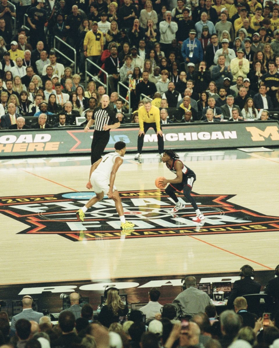 Malachi Smith drives down the court against Michigan while Head Coach Dusty May looks on in Lucas Oil Stadium in Indianapolis on April 6.