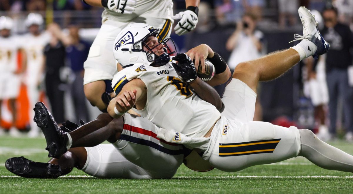 NAU quarterback Ty Pennington gets sacked by Chase Kennedy at Casino Del Sol Stadium on Sept. 5.