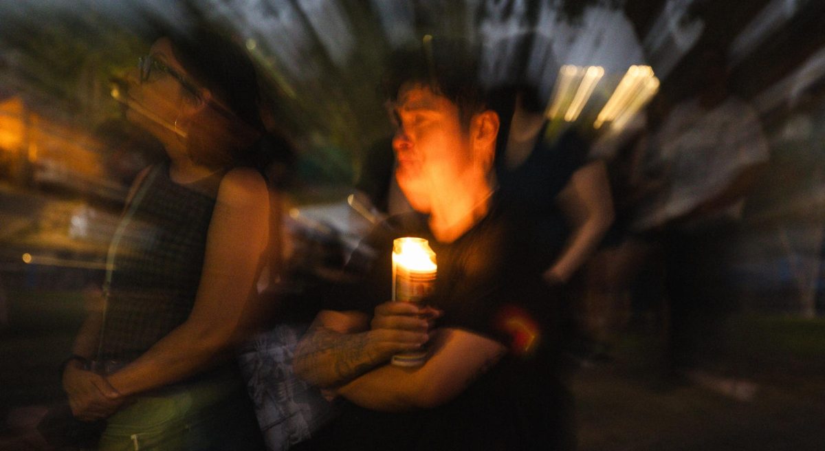 A community member sheds a tear while holding a candle at the vigil for the victims of the Venture-N shooting on Sept 2.