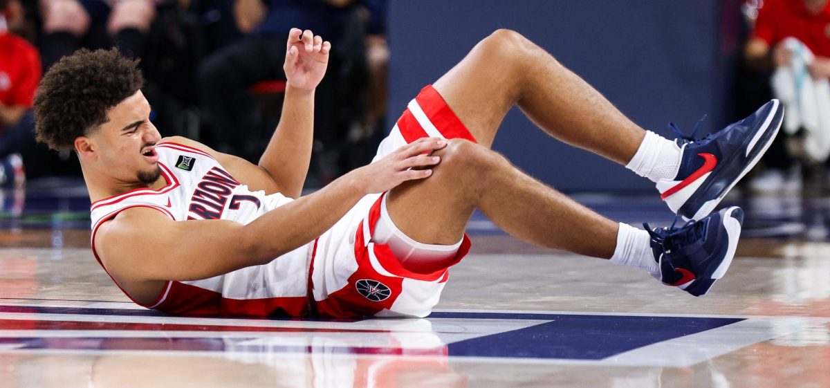 Derek Dixon grabs his knee after slipping in McKale Center at ALKEME Arena on Oct. 13.