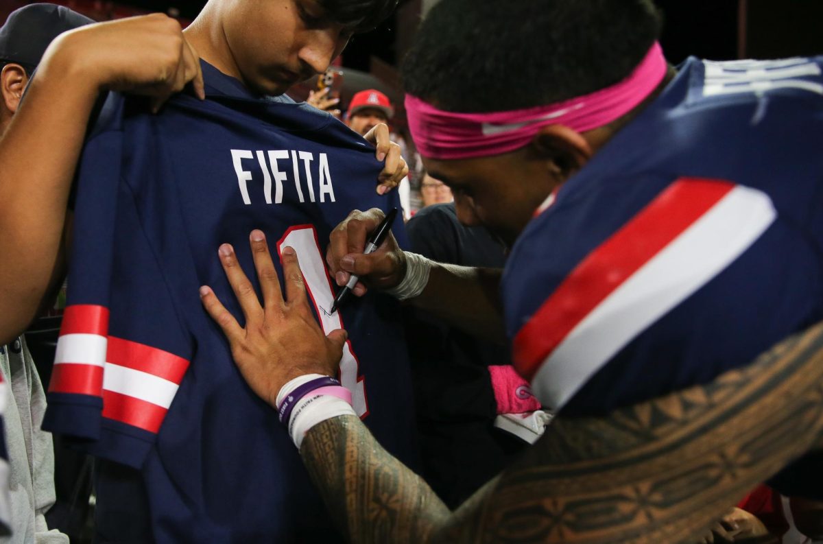 Noah Fifita signs a jersey after Arizona's win against Cincinnati on Oct. 3 at Casino Del Sol Stadium.